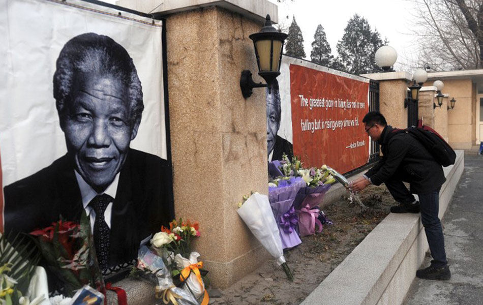 Seorang lelaki meletakkan sejambang bunga di sebuah potrait mendiang Nelson Mandela. -AFP PHOTO / WANG ZHAO Seorang lelaki meletakkan sejambang bunga di sebuah potrait mendiang Nelson Mandela. -AFP PHOTO / WANG ZHAO