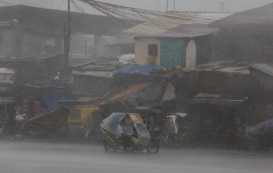 Seorang wanita duduk di dalam beca ketika mengharungi angin kencang dan hujan ketika kawasan Navotas dilanda Taufan Rammasun. -AP Photo/Aaron Favila Seorang wanita duduk di dalam beca ketika mengharungi angin kencang dan hujan ketika kawasan Navotas dilanda Taufan Rammasun. -AP Photo/Aaron Favila