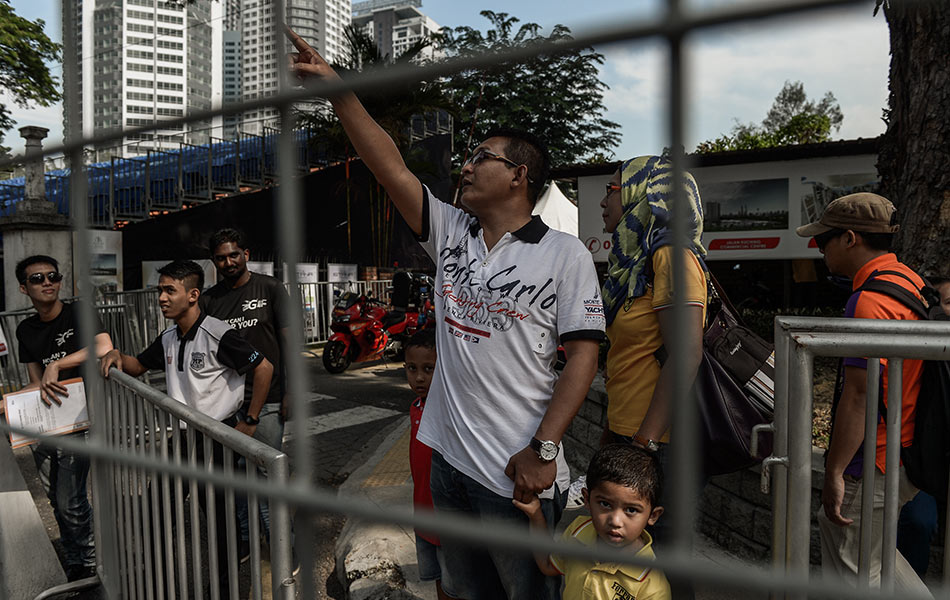 Pejalan kaki meminta pegawai keselamatan untuk menyeberangi trek lumba menjelang perlumbaan kereta pertama di Malaysia, KL City Grand Prix di Kuala Lumpur pada 7 Ogos, 2015. AFP PHOTO / MOHD RASFAN Pejalan kaki meminta pegawai keselamatan untuk menyeberangi trek lumba menjelang perlumbaan kereta pertama di Malaysia, KL City Grand Prix di Kuala Lumpur pada 7 Ogos, 2015. AFP PHOTO / MOHD RASFAN
