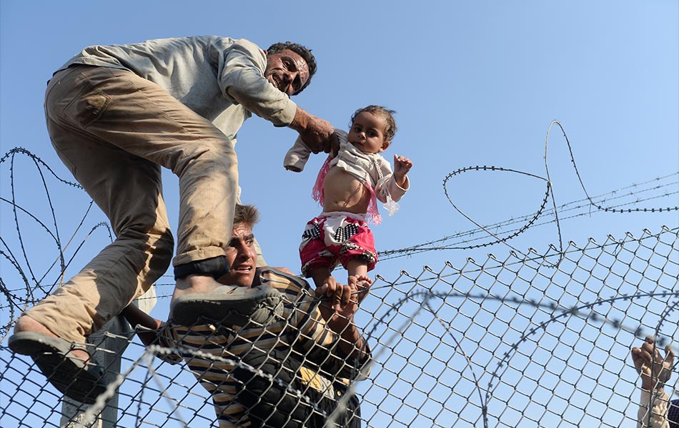 Seorang kanak-kanak Syria diangkat untuk melepasi pagar di sempadan Turki di Akcakale, wilayah Sanliurfa pada 14 Jun, 2015. AFP PHOTO / BULENT KILIC Seorang kanak-kanak Syria diangkat untuk melepasi pagar di sempadan Turki di Akcakale, wilayah Sanliurfa pada 14 Jun, 2015. AFP PHOTO / BULENT KILIC