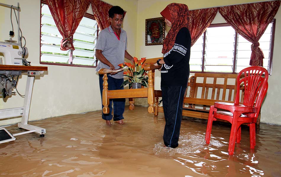 Rozali Man, 50, (kiri) bersama anaknya berusaha menyelamatkan barangan untuk diletakkan ke tempat tinggi selepas rumah mereka ditenggelami banjir ketika ditemui di Pekan Changlun pada Khamis, 17 September, 2015. - Foto BERNAMA Rozali Man, 50, (kiri) bersama anaknya berusaha menyelamatkan barangan untuk diletakkan ke tempat tinggi selepas rumah mereka ditenggelami banjir ketika ditemui di Pekan Changlun pada Khamis, 17 September, 2015. - Foto BERNAMA