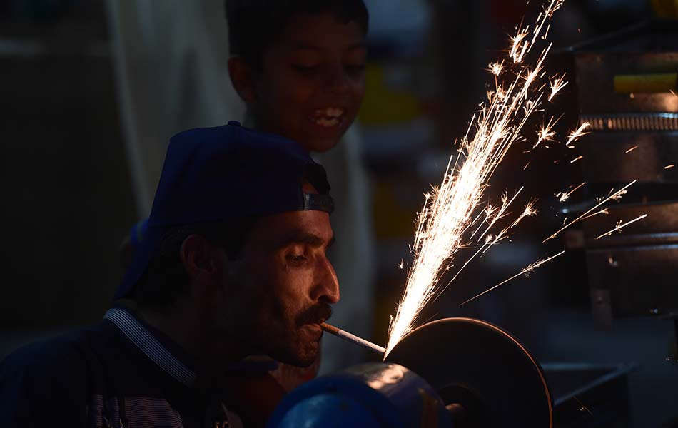 Seorang tukang besi menghibur seorang kanak-kanak dengan menyala rokok dengan pengasah pisau ketika membuat persediaan bagi Hari Raya Aidiladha di Rawalpindi, Pakistan pada 21 September 2015. - Foto AFP/Farooq Naeem Seorang tukang besi menghibur seorang kanak-kanak dengan menyala rokok dengan pengasah pisau ketika membuat persediaan bagi Hari Raya Aidiladha di Rawalpindi, Pakistan pada 21 September 2015. - Foto AFP/Farooq Naeem