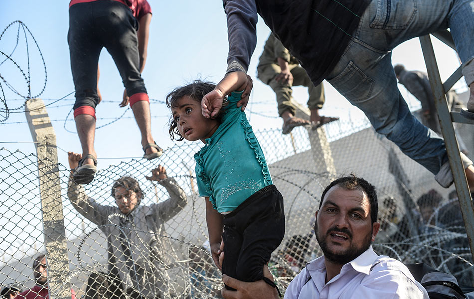 Seorang kanak-kanak Syria diangkat untuk melepasi pagar di sempadan Turki di Akcakale, wilayah Sanliurfa pada 14 Jun, 2015. AFP PHOTO / BULENT KILIC Seorang kanak-kanak Syria diangkat untuk melepasi pagar di sempadan Turki di Akcakale, wilayah Sanliurfa pada 14 Jun, 2015. AFP PHOTO / BULENT KILIC