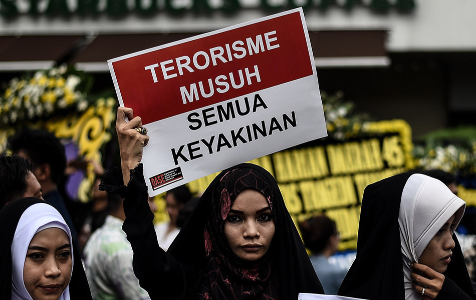 Foto diambil pada 15 Januari 2016, seorang wanita memegang sepanduk di luar kedai kopi Starbucks yang rosak akibat siri letupan di Jakarta. - AFP PHOTO / MANAN VATSYAYANA Foto diambil pada 15 Januari 2016, seorang wanita memegang sepanduk di luar kedai kopi Starbucks yang rosak akibat siri letupan di Jakarta. - AFP PHOTO / MANAN VATSYAYANA