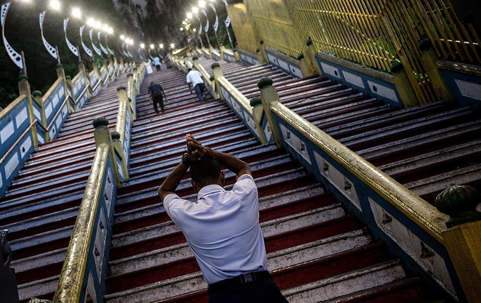 Seorang penganut Hindu bersembahyang di tangga masuk kuil Batu Caves, Selangor, Malaysia pada 12 Januari 2016. AFP PHOTO / MANAN VATSYAYANA / Seorang penganut Hindu bersembahyang di tangga masuk kuil Batu Caves, Selangor, Malaysia pada 12 Januari 2016. AFP PHOTO / MANAN VATSYAYANA /