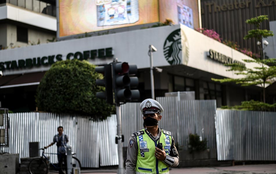 Seorang anggota polis Indonesia berdiri mengawal di hadapan bangunan Starbucks yang musnah di Jakarta pada 15 Januari 2016, sehari selepas satu siri letupan melanda ibu negara Indonesia. AFP PHOTO / MANAN VATSYAYANA Seorang anggota polis Indonesia berdiri mengawal di hadapan bangunan Starbucks yang musnah di Jakarta pada 15 Januari 2016, sehari selepas satu siri letupan melanda ibu negara Indonesia. AFP PHOTO / MANAN VATSYAYANA