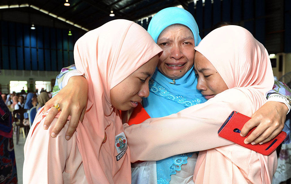 Twins Nur Fatiha Abdul Rahman (left) and Nur Fatihana Abdul Rahman from SK Puteri, Seremban hugs their mother Nozailinda Nik Mohd Noor (centre) after receiving the UPSR results. The twins scored 6As. - fotoBERNAMA