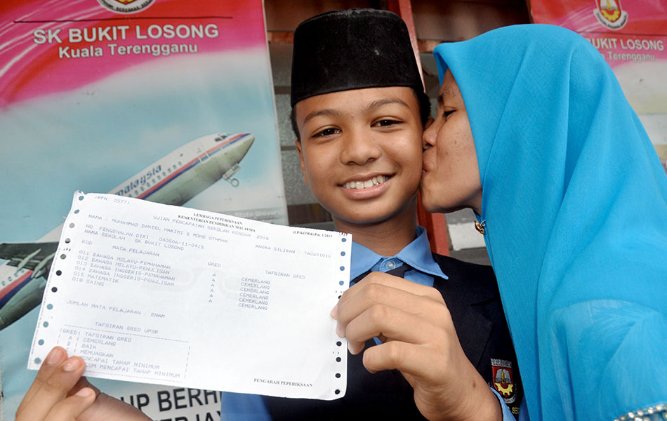 Single mother Hasmah Razak,39, kisses her son Muhammad Daniel Hakimi Mohd Othman of SK Bukit Losong, Kuala Terengganu after he scored 6As in the UPSR examinations. Muhammad Daniel lost his father at age 2. - fotoBERNAMA