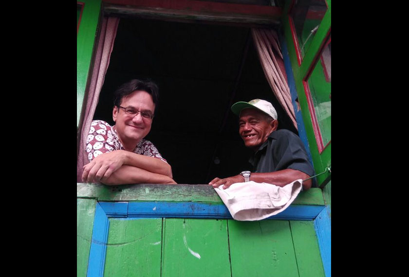 Pak Teguh looking out the window of his home alongside Karim. - Photo by Karim Raslan