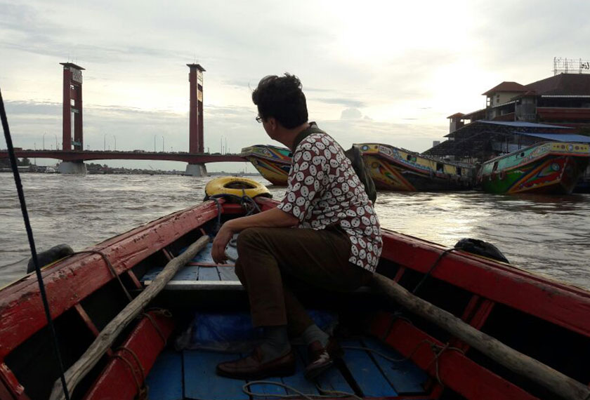 Karim Raslan riding the ketek across the Musi River. A ketek is a sleek, wooden-hulled motorized boat that is only about six metres long and serves as a water taxi on the high-traffic Musi River. - Photo by Karim Raslan