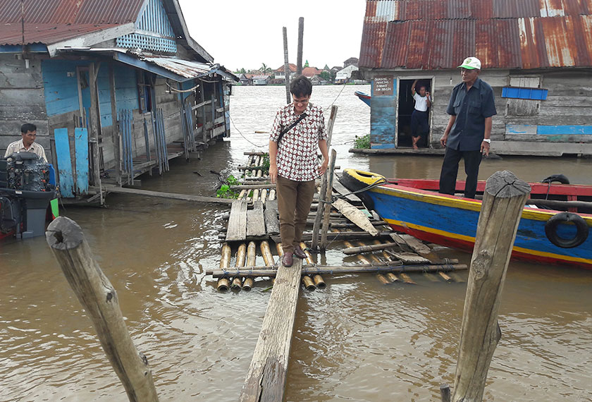 Karim precariously crosses the makeshift bridge connecting the dock to land. - Photo by Karim Raslan