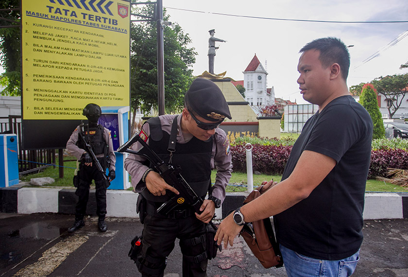 An armed police officer checks a visitor’s messenger bag at the entrance to Surabaya’s police headquarters. Fully Syafi/Ceritalah