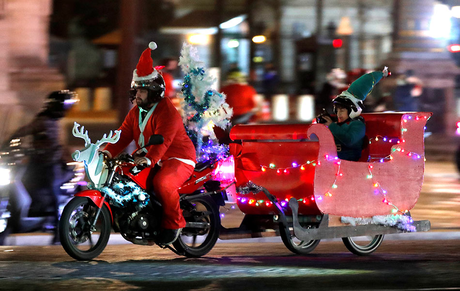 Seorang lelaki berpakaian Santa Klaus menunggang motosikal sambil menarik penolongnya sempena perarakan 'Carabalade' di Paris, Perancis pada 20 Disember 2018. - Foto Reuters/Charles Platiau Seorang lelaki berpakaian Santa Klaus menunggang motosikal sambil menarik penolongnya sempena perarakan 'Carabalade' di Paris, Perancis pada 20 Disember 2018. - Foto Reuters/Charles Platiau