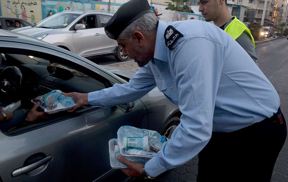 Seorang pegawai polis mengedarkan makanan ringan kepada pengguna jalan raya di Bandar Gaza sejurus sebelum waktu berbuka puasa pada 13 Mei 2019. - Foto AP/Hatem Moussa Seorang pegawai polis mengedarkan makanan ringan kepada pengguna jalan raya di Bandar Gaza sejurus sebelum waktu berbuka puasa pada 13 Mei 2019. - Foto AP/Hatem Moussa