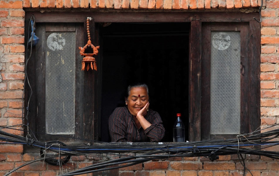 Wanita ini menguntum senyum saat meninjau persekitaran kediamannya dari jendela rumah di sebuah perkampungan lama di Kathmandu, Nepal, yang kini dalam perintah kawalan pergerakan. - Reuters/Navesh Chitrakar Wanita ini menguntum senyum saat meninjau persekitaran kediamannya dari jendela rumah di sebuah perkampungan lama di Kathmandu, Nepal, yang kini dalam perintah kawalan pergerakan. - Reuters/Navesh Chitrakar