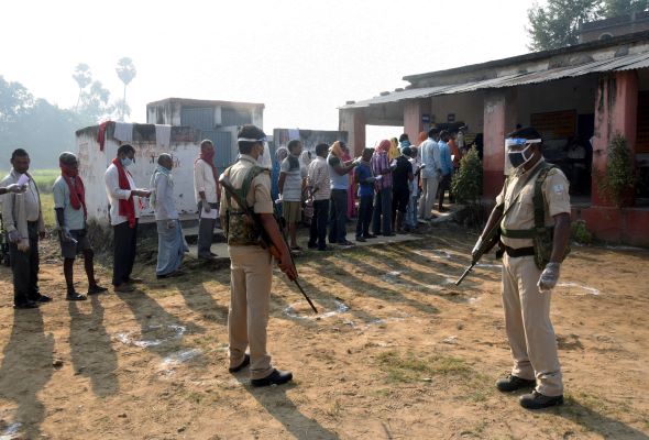 Voters lining up on the first day of a three-phase election for a new legislature in Bihar state were met with masks and temperature checks. Voters lining up on the first day of a three-phase election for a new legislature in Bihar state were met with masks and temperature checks.