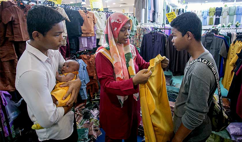 Penerima Sumbangan Tunai Rahmah (STR) Nor Hanis Hashim, 34 (dua,kiri) membeli pakaian raya untuk anak-anaknya ketika ditemui di salah sebuah pasaraya di sini semalam. - Foto Bernama