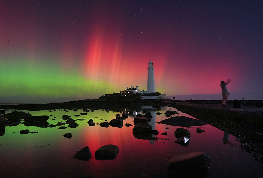 Aurora borealis kelihatan bersinar di langit berhampiran Rumah Api St Mary di Whitley Bay, pantai timur laut England, 12 Nov 2025. (Foto AP)